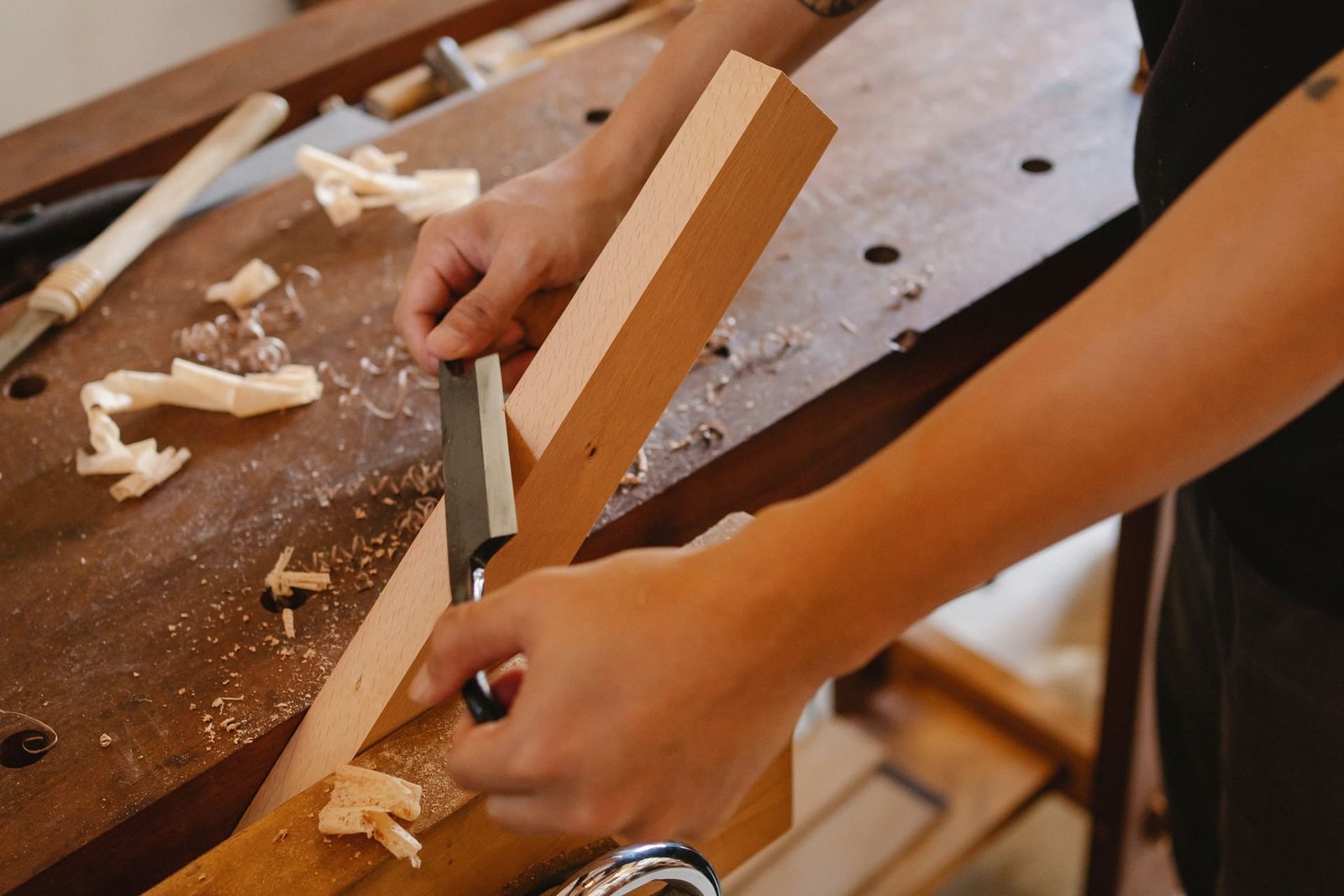 A carpenter paring a beech board with a chisel at a workbench